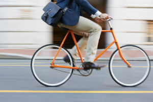 man orange riding bike through city