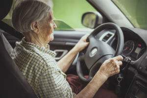 elderly woman with hands on steering wheel