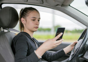 young woman driving while texting