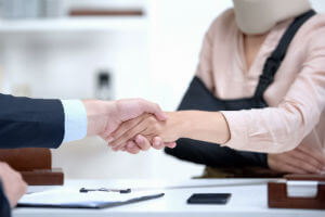 person-with-sling-shaking-lawyers-hand