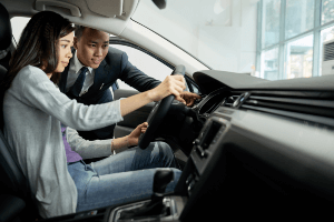 man showing a woman the functions of a vehicle before purchase