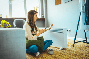 woman warming herself next to a personal space heater