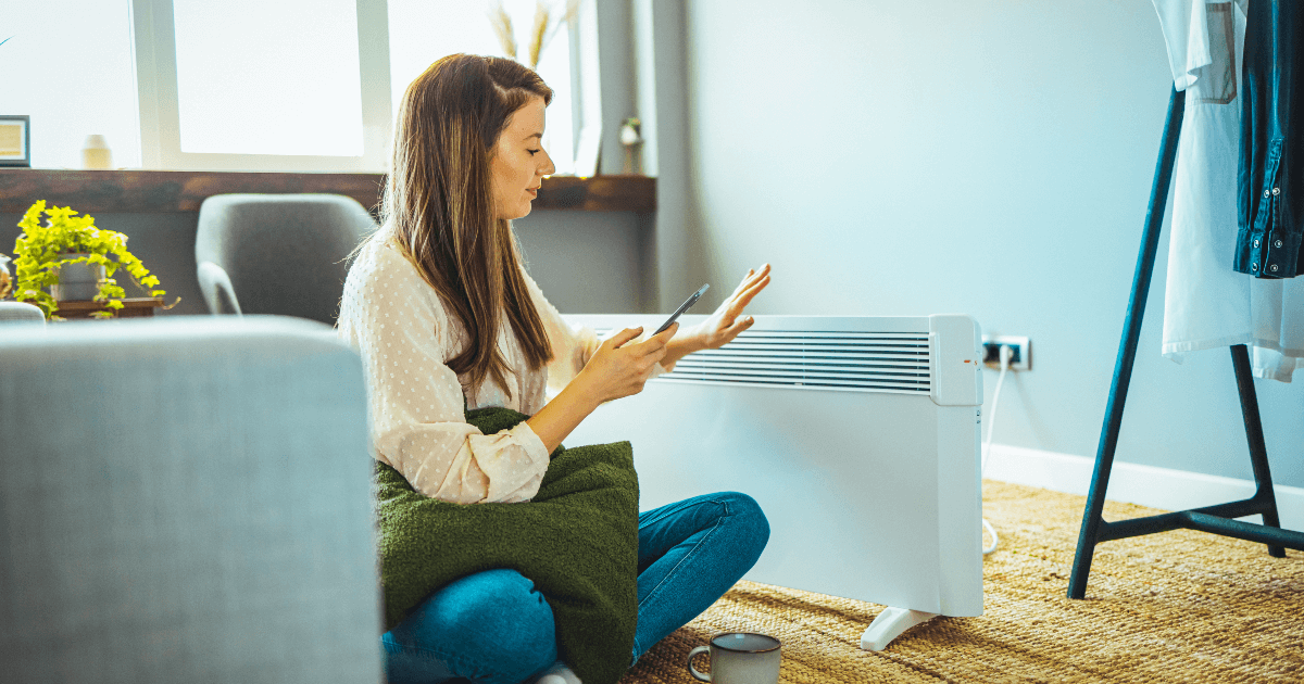 woman warming herself next to a personal space heater