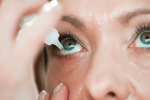 Woman putting eye drops in her eye