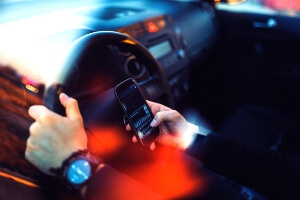 photo illus shows hands of a driver texting