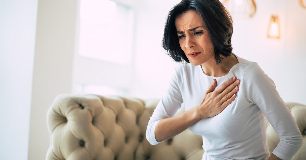 young woman at home clutching her chest in pain