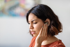 Young woman holding ear in pain