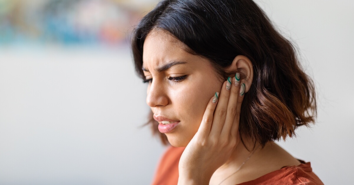 Young woman holding ear in pain