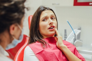 Young woman at dentist holding her jaw in pain