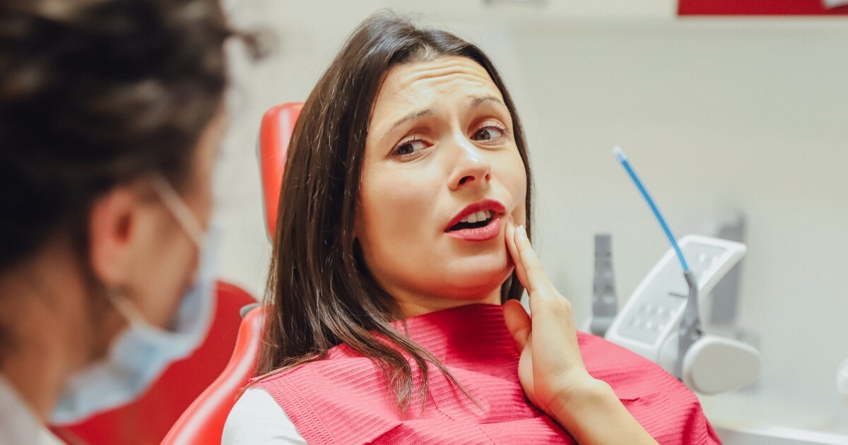 young woman at dentist holding her jaw in pain