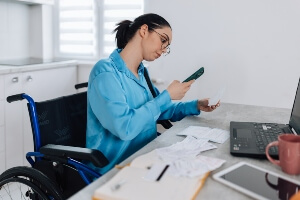 woman in wheelchair inputting expenses to her computer