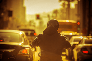 Motorcyclist driving through heavy traffic while the sun sets. 