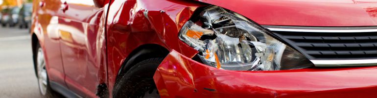 A red car that has been involved in an accident, possibly a hit and run, and sustained damage.