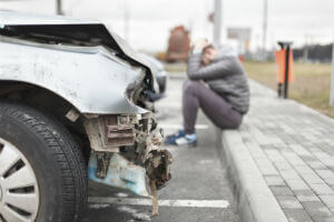 car accident victim sitting outside of car
